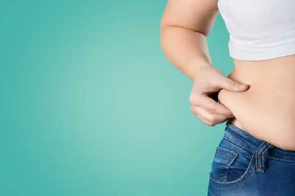 Image of woman pinching her love handles to show weight gain Belper